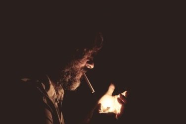 Image of a man lighting a cigarette, representing the often-asked question 'Does smoking cause mesothelioma?' and how the attorneys at Nemeroff Law Firm can answer that and other questions related to mesothelioma.