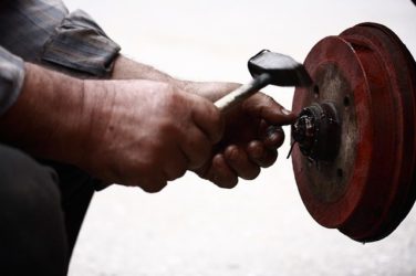 Image of a brake disc being worked on by a mechanic, a situation that might cause those nearby to wonder: What is bystander asbestos exposure and might I be affected?