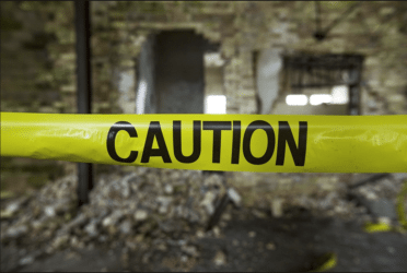 Image of a crumbling building with caution tape, representing the danger of popcorn ceiling asbestos in homes and other structures.